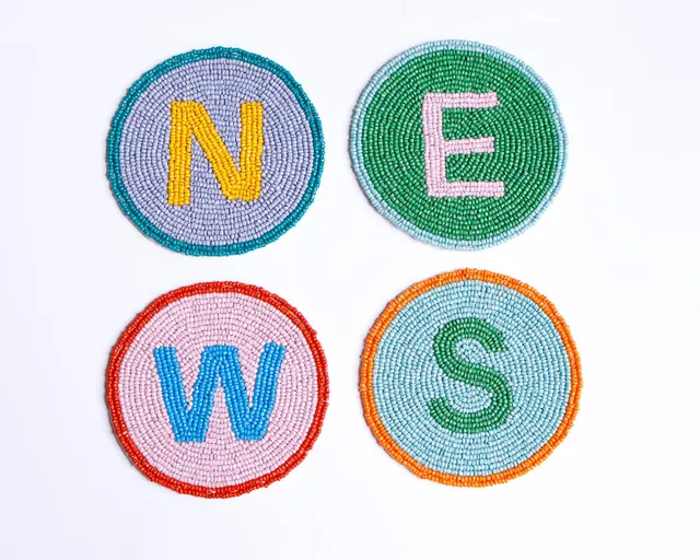 Hand-beaded NEWS coasters with colorful beadwork on felt backing.